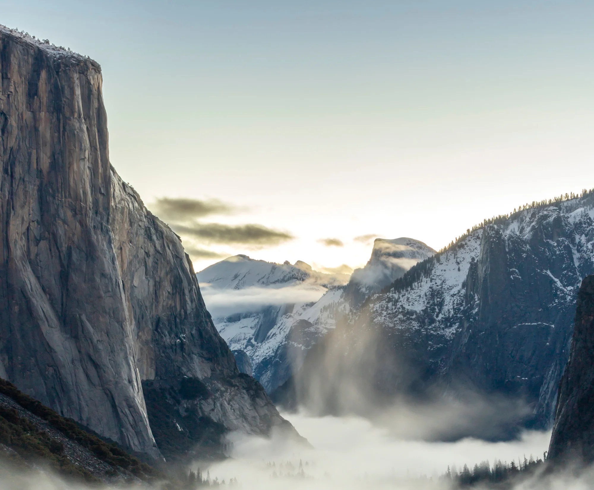 Yosemite Valley at sunrise, with El Capitan and Half Dome rising above a bank of fog